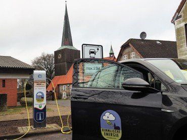 Elektroauto an Ladesäule vor Kirche.