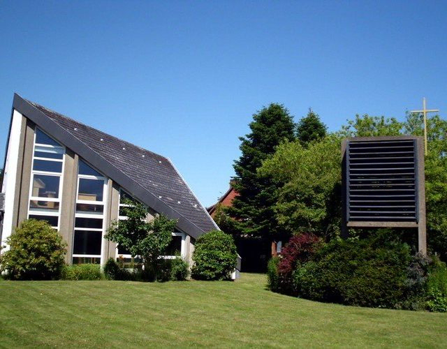 Moderne Kirche mit schrägem Dach und Garten.