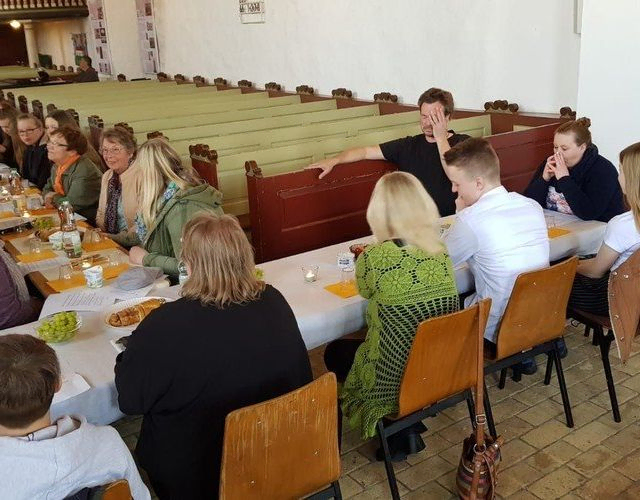 Menschen bei einem Abendessen in einem Saal.